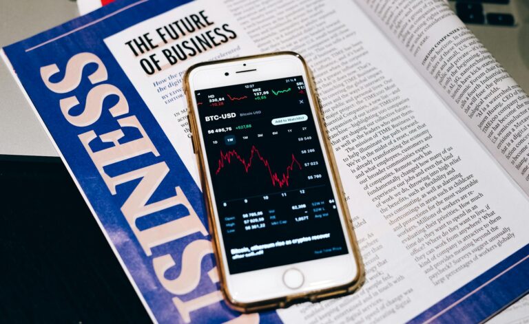 Close-up of a smartphone displaying a cryptocurrency price graph on a business magazine.